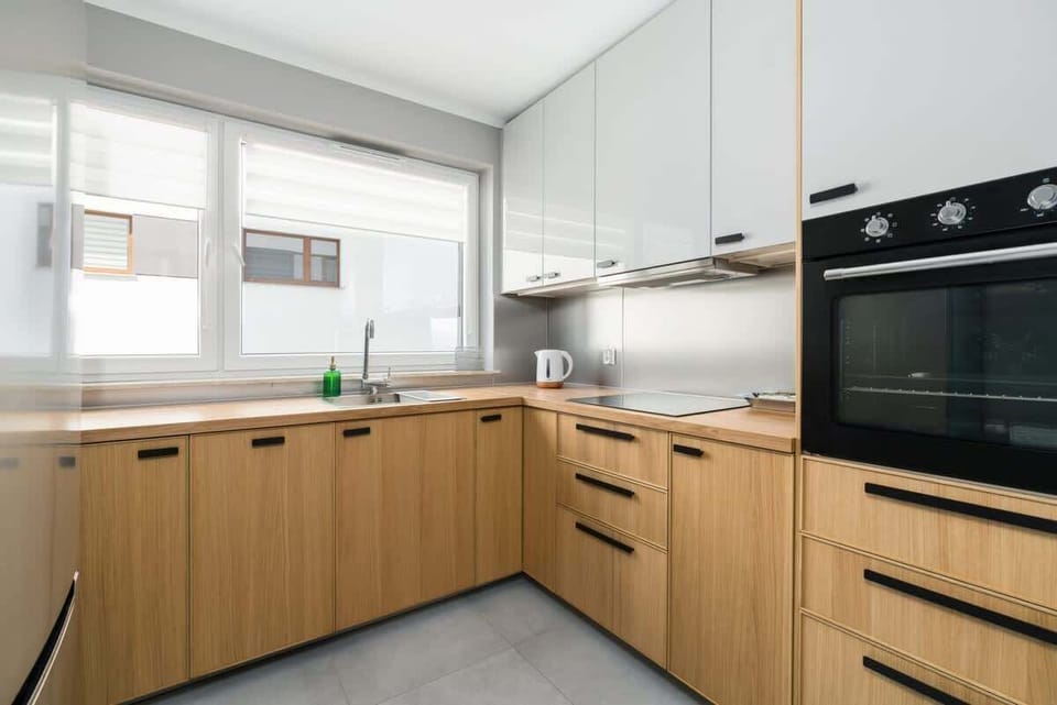 A bright kitchen with wooden cabinetry, white walls, and modern appliances, offering a clean and functional design.