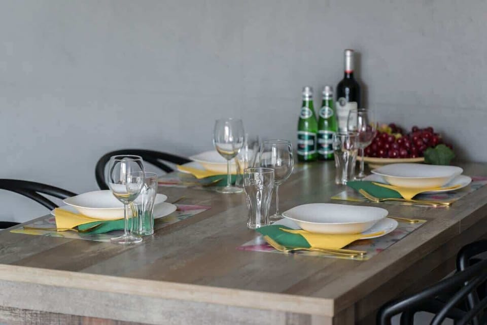 A dining table setup featuring glasses, plates, and a bottle of wine, ready for a meal.