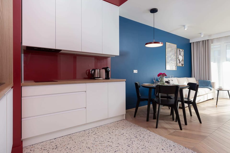 Functional kitchenette with white cabinets with a burgundy wall between them matches the rest of the room.