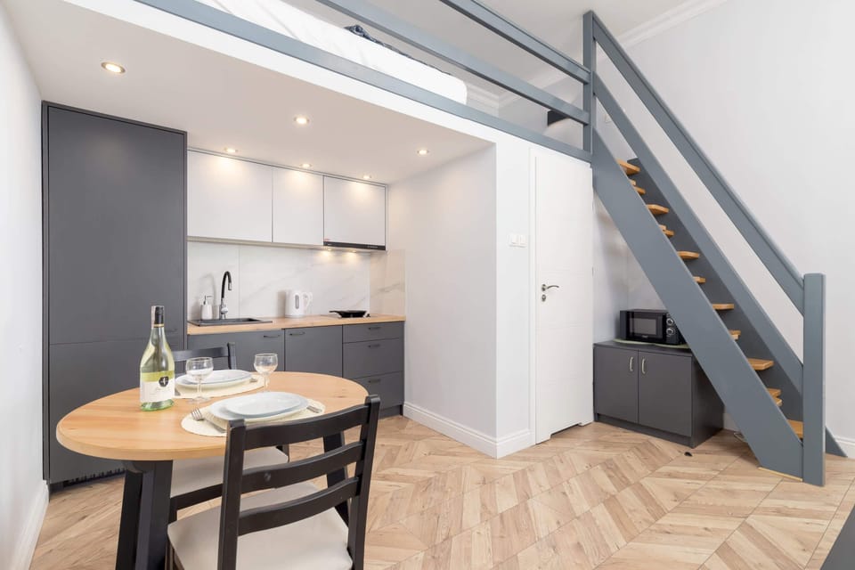 Kitchen area with dining space, featuring a small round table, two chairs, and a staircase to the loft.