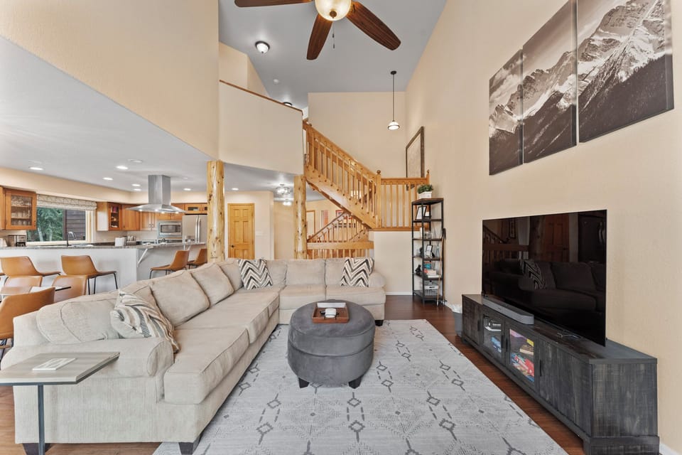 Unwind in your spacious living room with plush sectional seating and mountain artwork, while the open kitchen awaits your culinary adventures.
