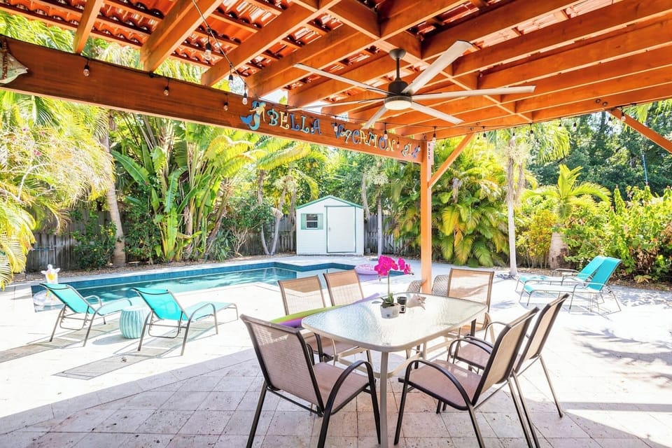 Poolside dining under a stylish pergola in Dania Beach, surrounded by greenery