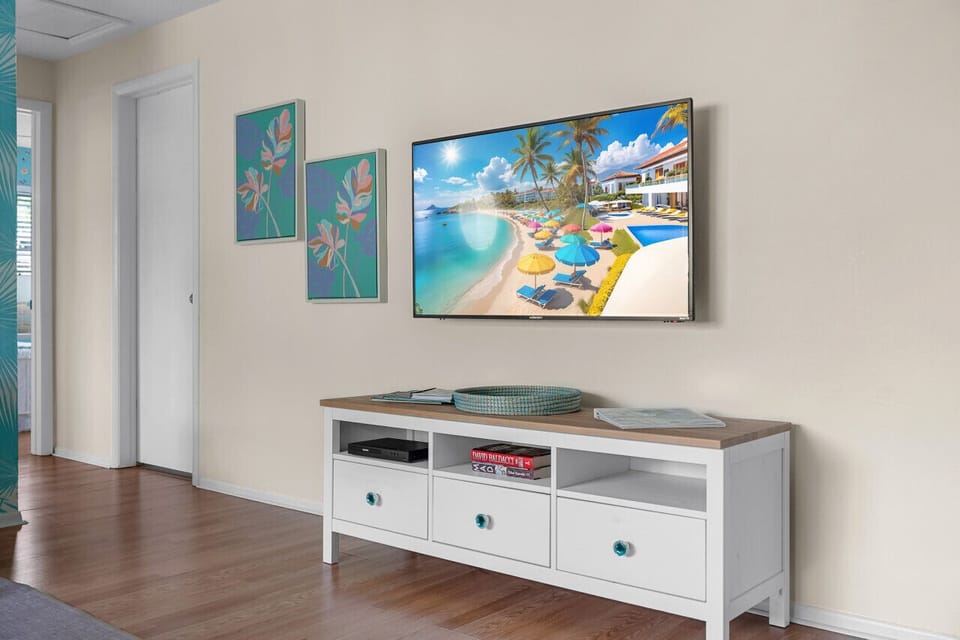 Escape to paradise in your living room! Beach vibes, tropical art, and sleek entertainment create a serene retreat.