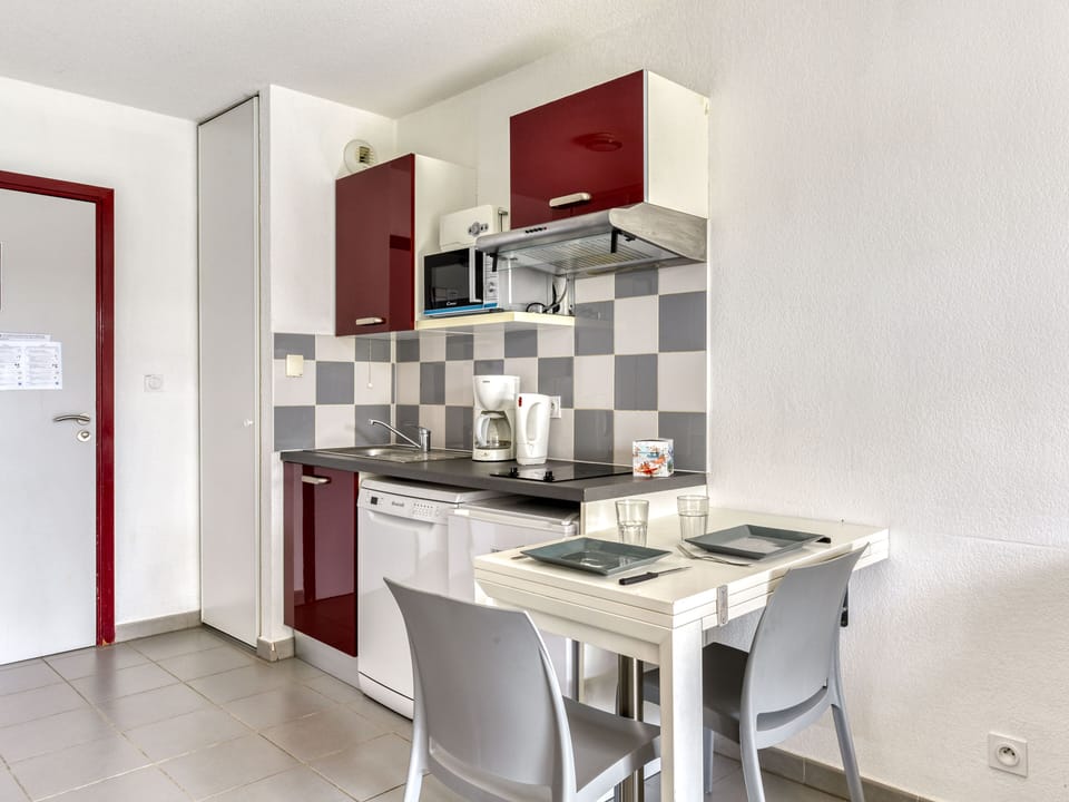 The modern kitchenette features sleek red cabinets and essential appliances, offering both functionality and comfort for preparing delightful meals during your vacation.