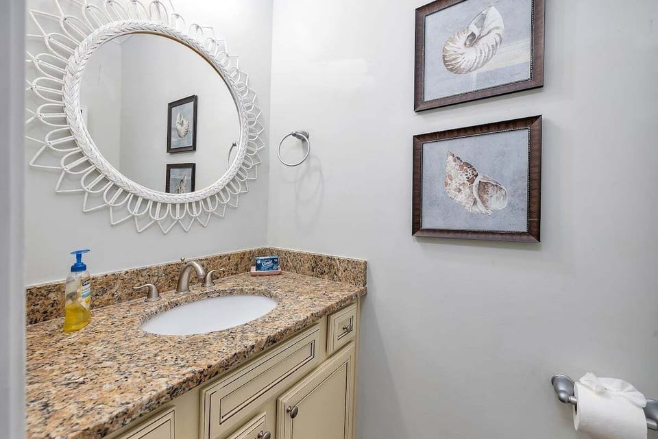 Bathroom vanity with granite counter and round decorative mirror