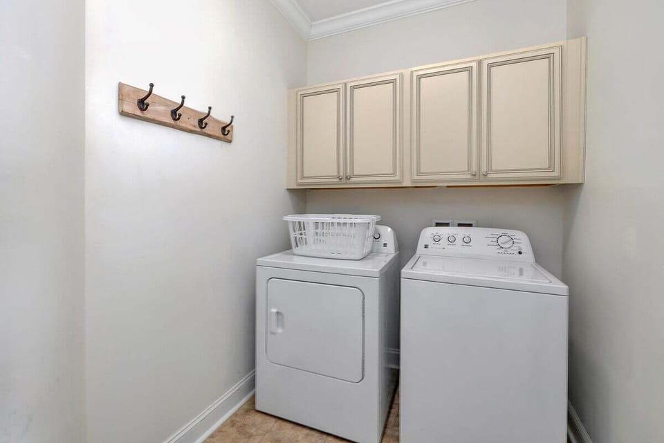 Laundry room with washer, dryer, and upper cabinets