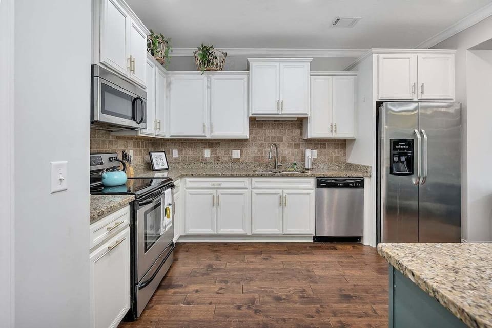 Kitchen with white cabinets, granite counters, and stainless appliances