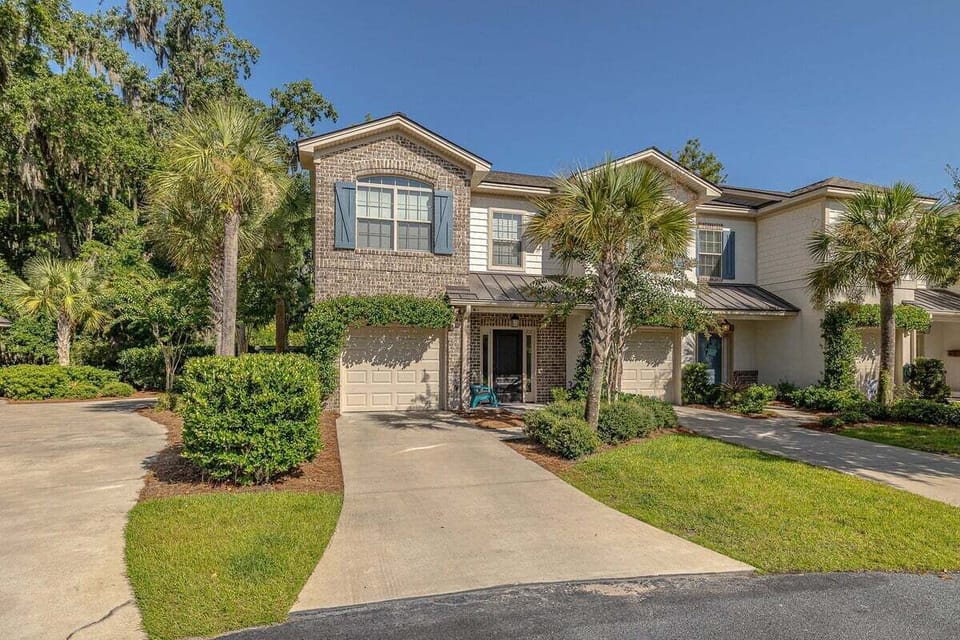Two-story brick property exterior with palm trees and garage