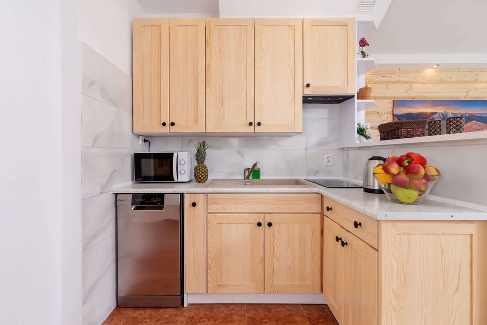 A compact yet fully equipped kitchenette with light wooden cabinets, a stovetop, and ample counter space. Its functional design ensures convenience.