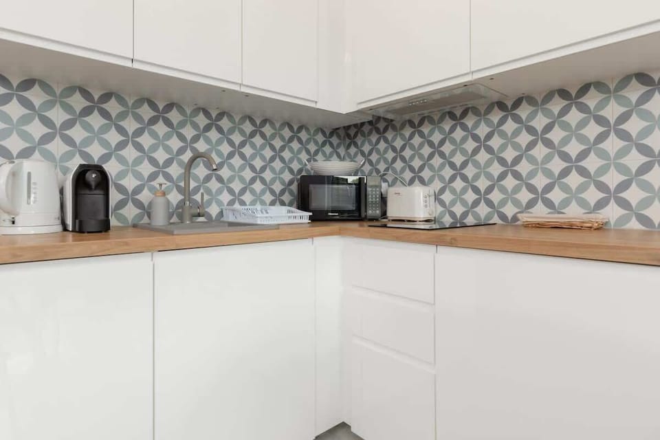 A bright kitchen with white cabinetry, modern appliances, and a backsplash with geometric patterns.