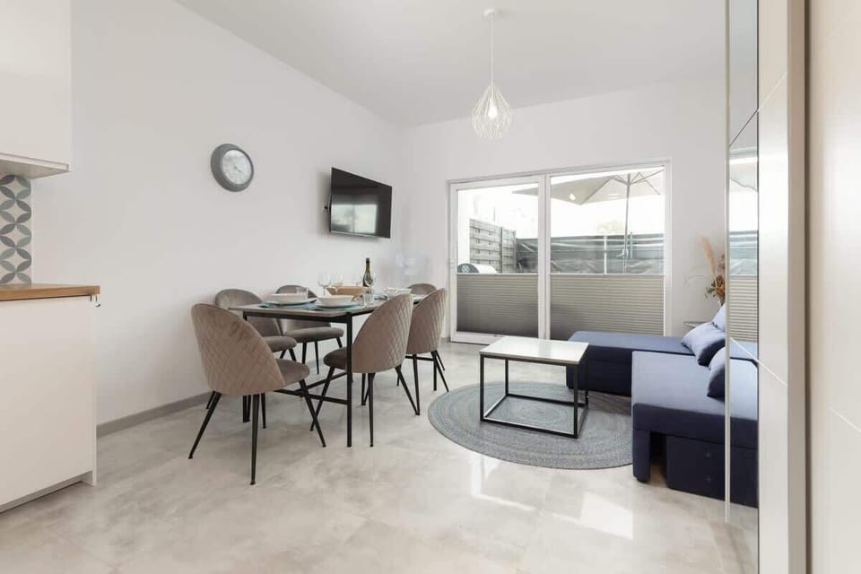 A stylish living room featuring a blue sofa, a coffee table, and a dining area with modern chairs, blending comfort and practicality.