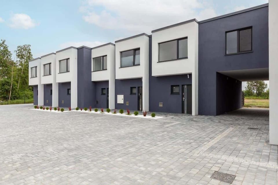A view of the modern townhouse-style residential building, with clean architectural lines and parking spaces.