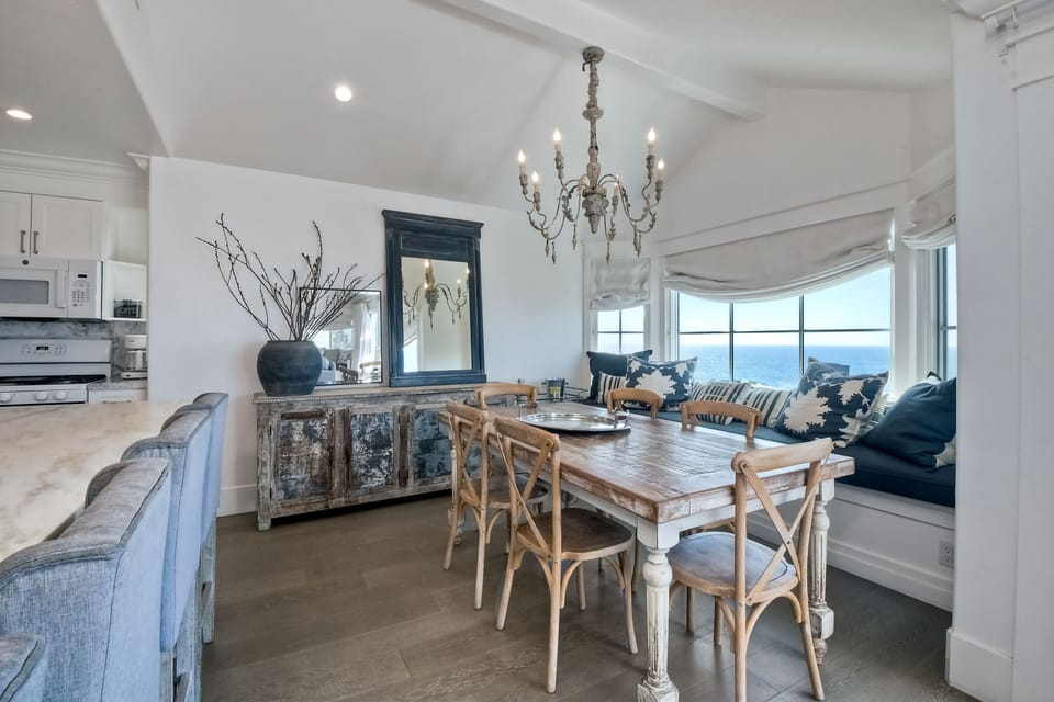 Stunning coastal dining area features an open-concept design with vaulted ceilings and breathtaking ocean views