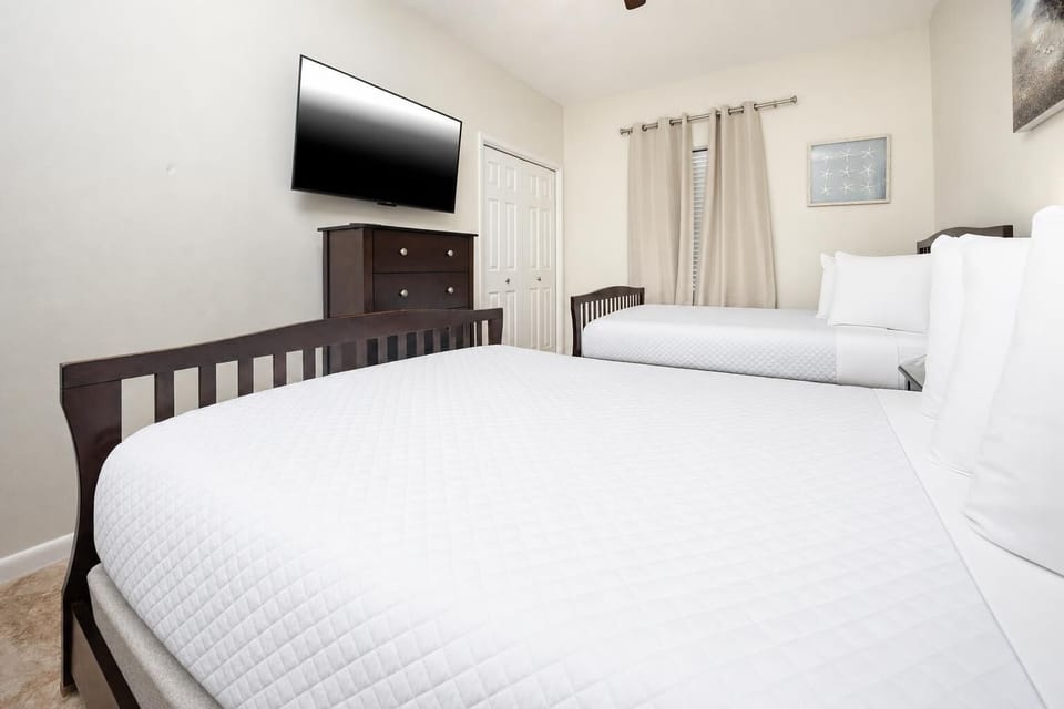 Guest room featuring two double beds, a flat-screen TV, and soft curtains, creating a serene and restful atmosphere