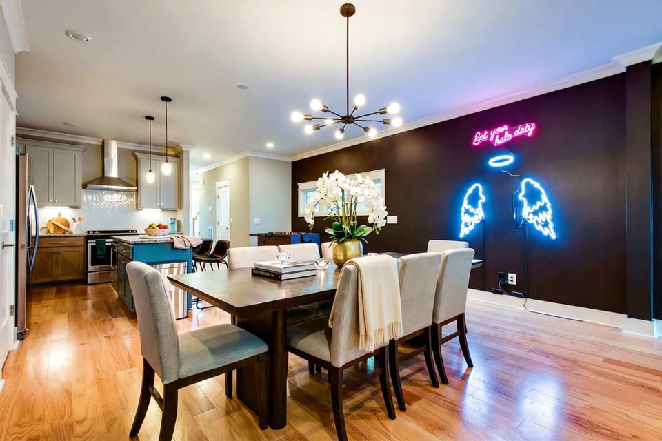Full dining setup with a chandelier, table for the whole crew, and neon accents keeps meals and group moments centered in one welcoming room