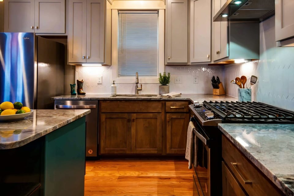 Chef's kitchen with marble counters, stainless steel appliances, and a window over the sink makes cooking for a crowd feel effortless