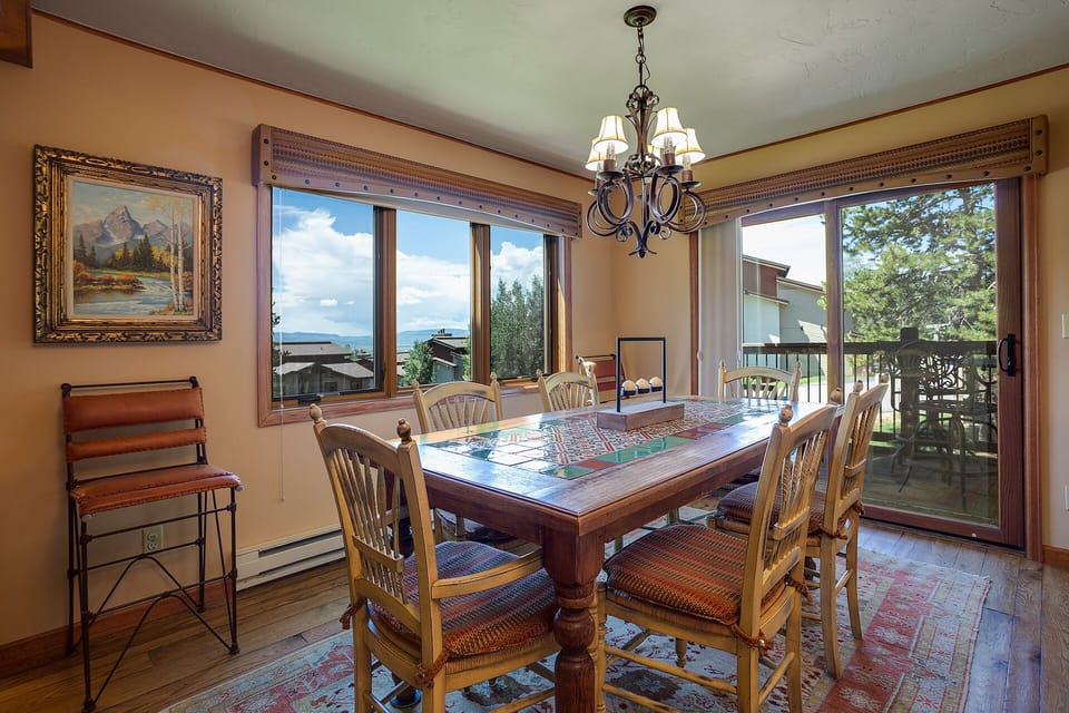 Your dining room features a rustic table with mountain views through panoramic windows, creating the perfect spot for memorable meals.
