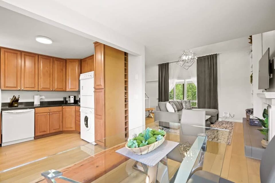 The charming kitchen boasts ample cabinets, modern black countertops, bright, white appliances, including a stacked washer and dryer, and everything you need to feel at home from a toaster to a coffee maker.