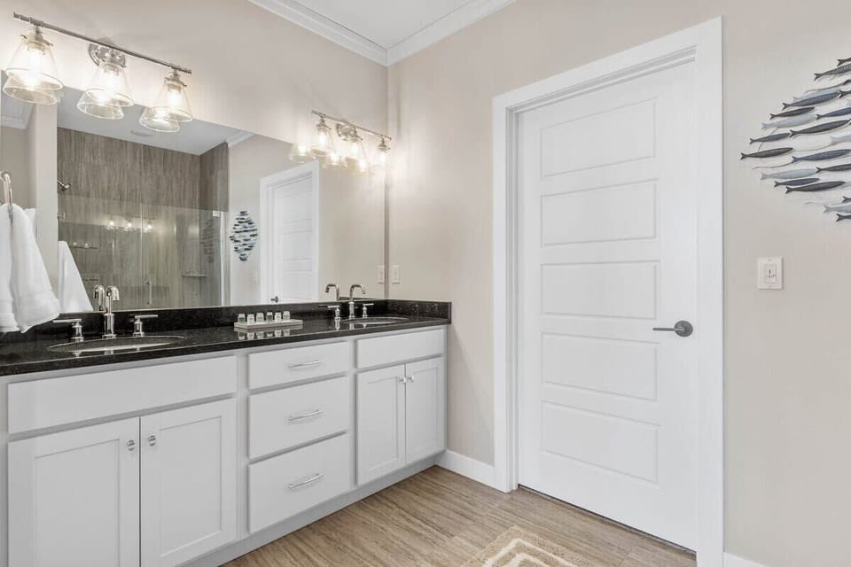 Modern bathroom vanity with white cabinetry, dark countertops, sleek fixtures, and a spacious layout.