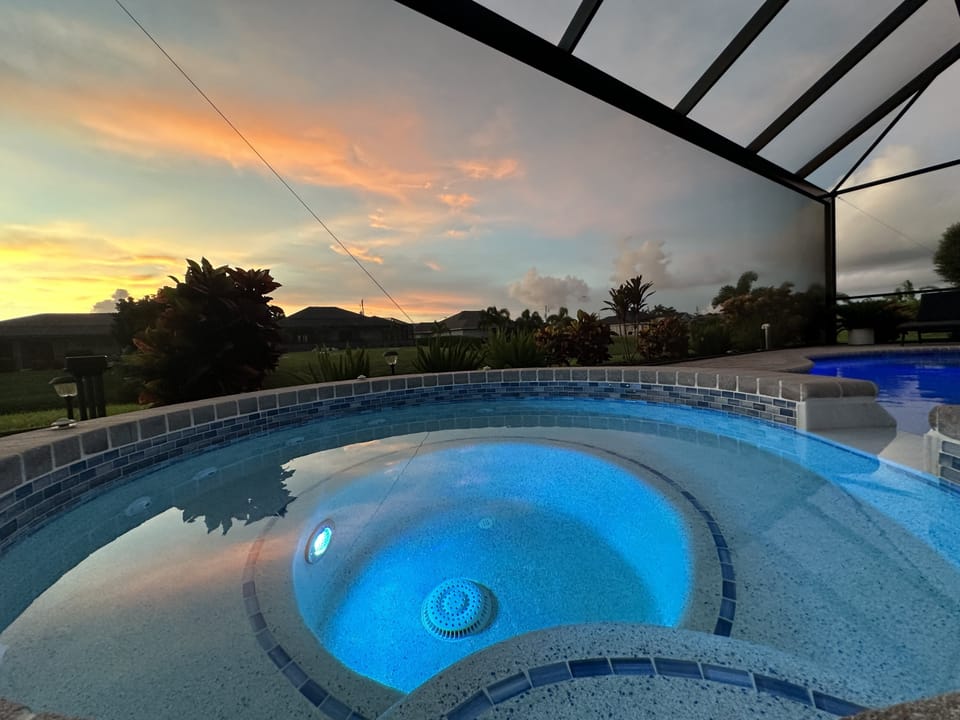 Relaxing pool with a spa section, enclosed in a lanai for sunset views