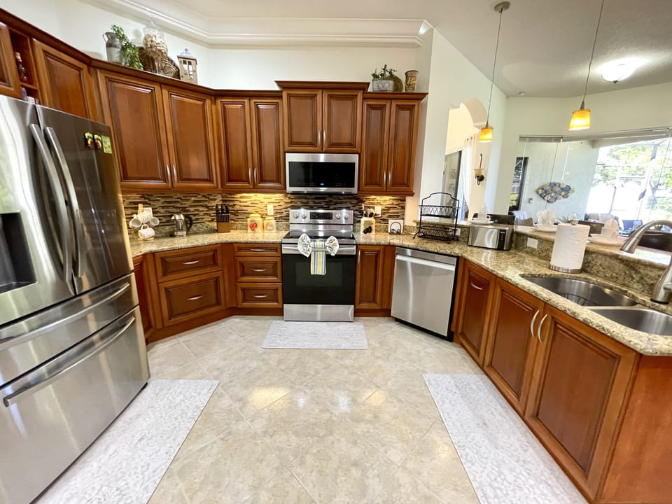 Modern kitchen with stainless steel appliances and cherry wood cabinets.
