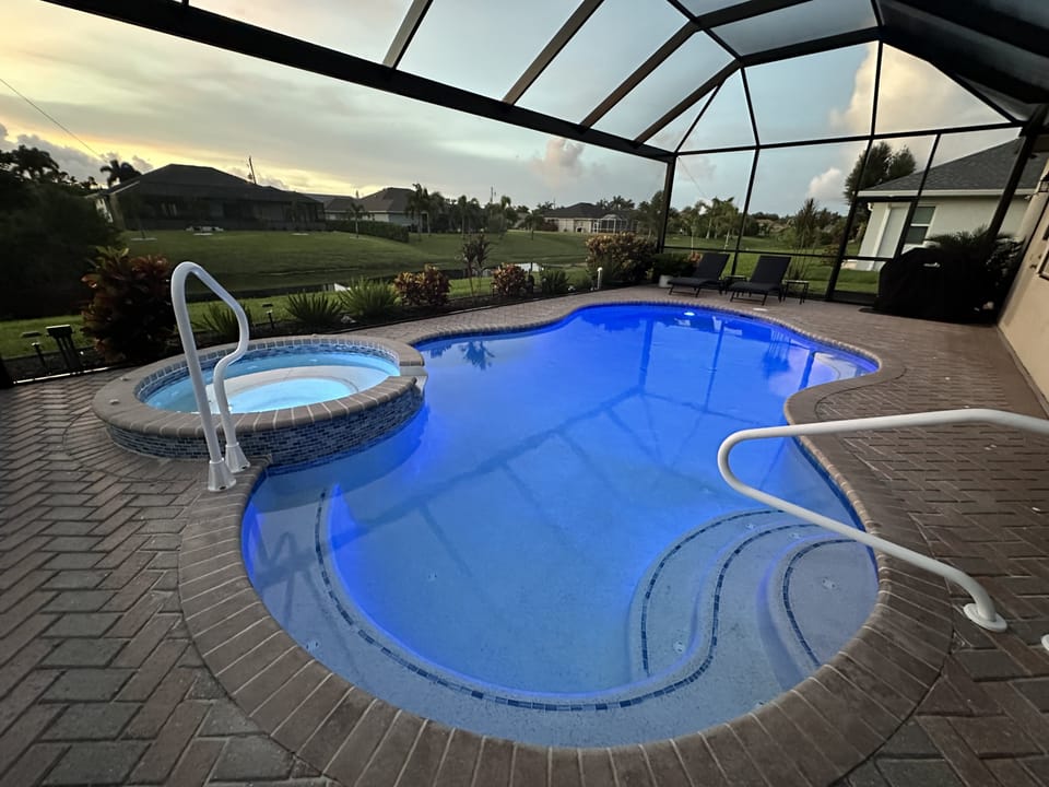 Inviting pool with a hot tub and screen enclosure, perfect for relaxing evenings.