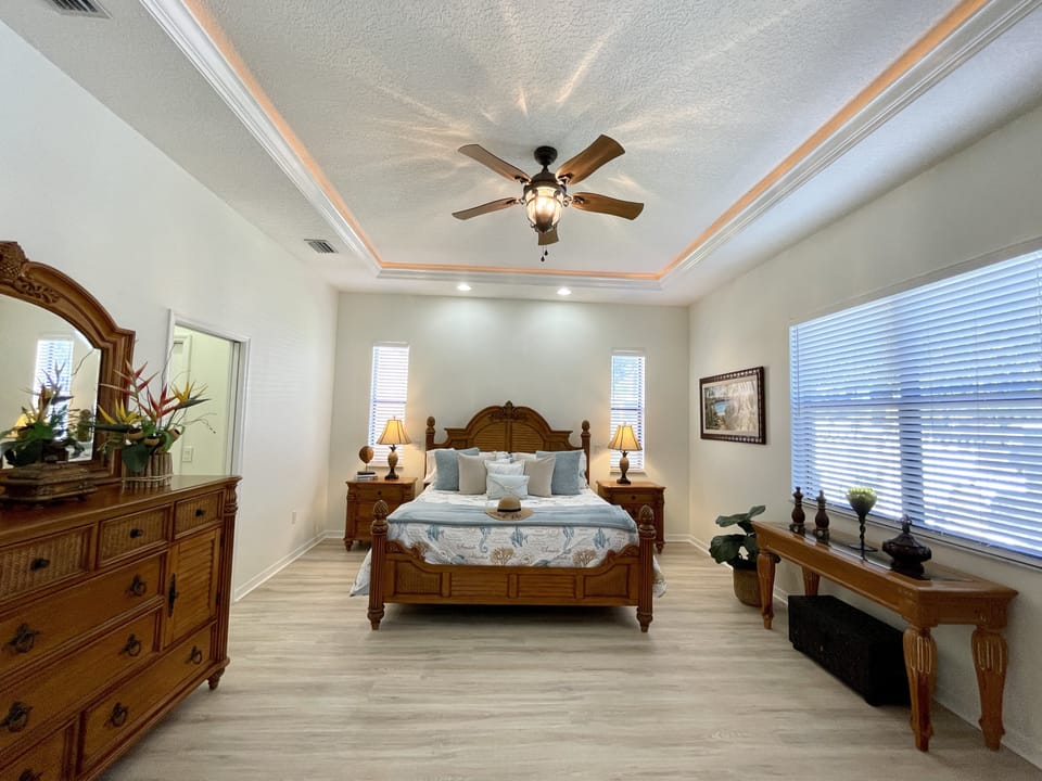 Elegant master bedroom with a classic king-sized bed and ample natural light.