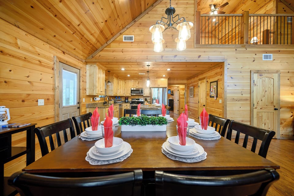 Gather around this beautifully set dining table beneath soaring wood ceilings, where the open kitchen invites your group to share meals and memories together in cozy cabin style.