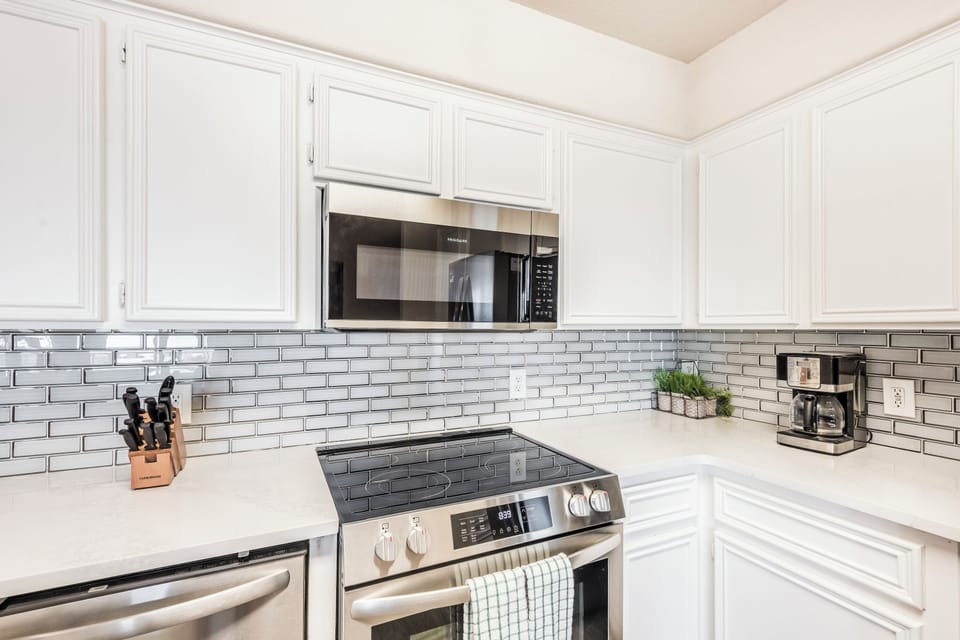 Your fully-equipped kitchen features gleaming white cabinets, stainless appliances, and elegant subway tile—perfect for morning coffee or preparing your favorite meals.