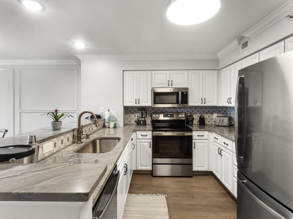 Your fully equipped gourmet kitchen awaits with pristine white cabinets, granite countertops, and stainless steel appliances for memorable home-cooked meals.