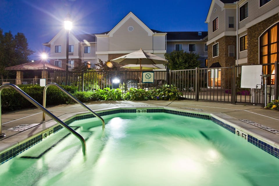 Sun-soaked pool deck with a row of loungers and clear blue water