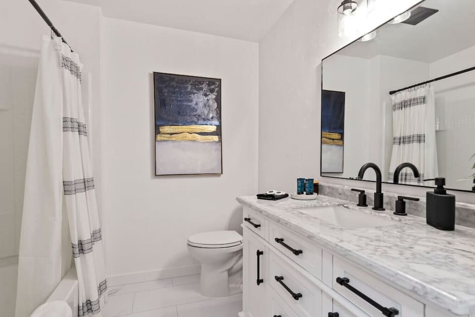 Shared bathroom with a tub, toilet, and ample vanity space