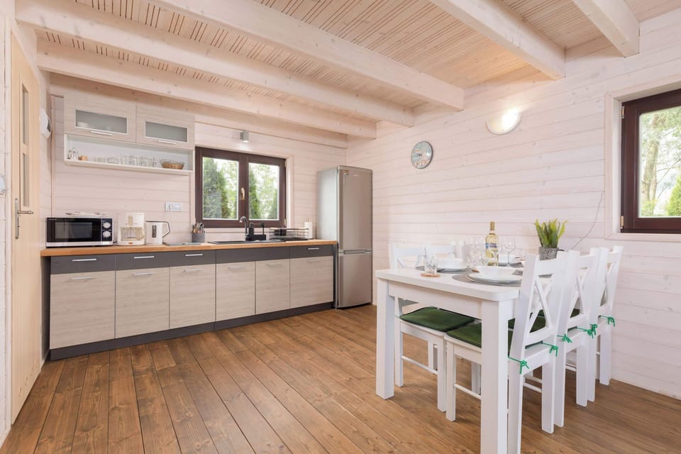 A bright kitchen corner with modern cabinetry and a dining table placed right next to the window. Simple decor and natural wood finishes give the space a clean and relaxing feel. It’s a perfect spot for shared meals in a calm setting.