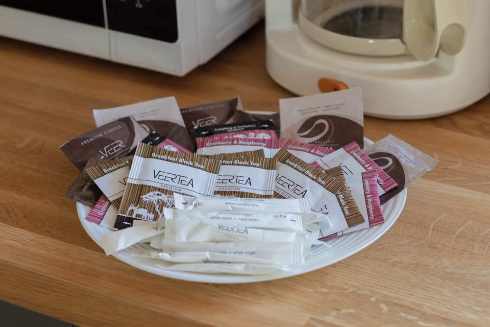 A tray with coffee and tea essentials, including cups, sugar, and assorted sachets. Everything is neatly arranged, creating a welcoming and thoughtful touch for guests. It invites you to start the day with a warm drink.