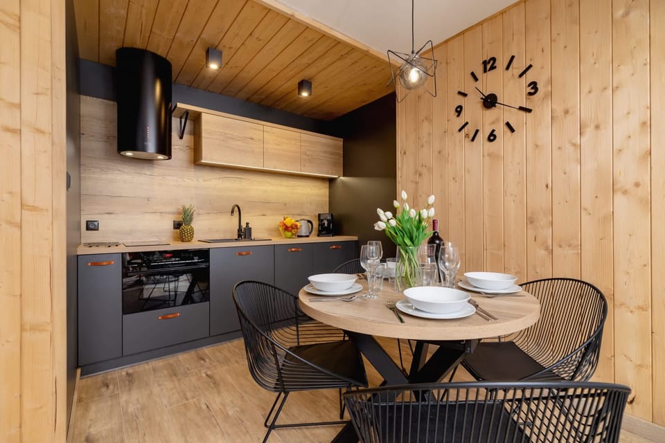 A modern dining and living area featuring wooden beams and bright natural lighting.