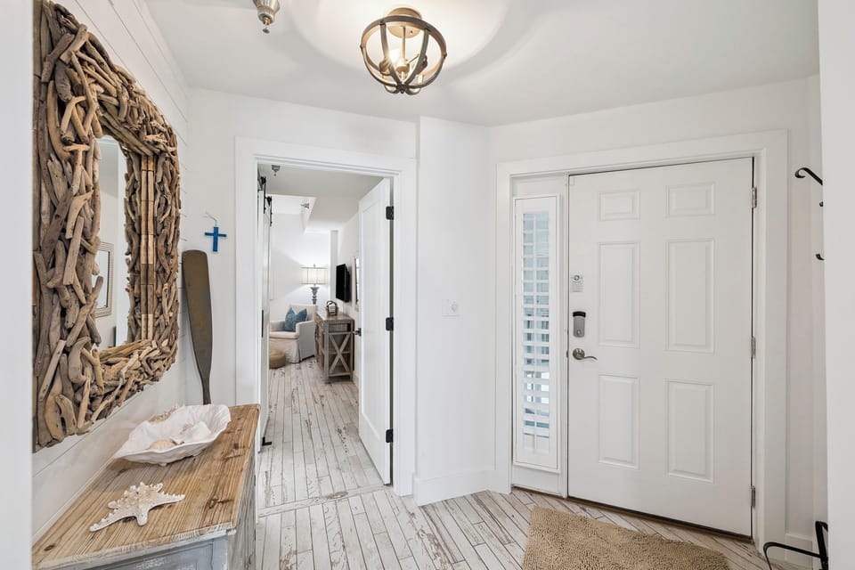 Step into coastal elegance with rustic wood floors, driftwood mirror, and nautical touches welcoming you home.