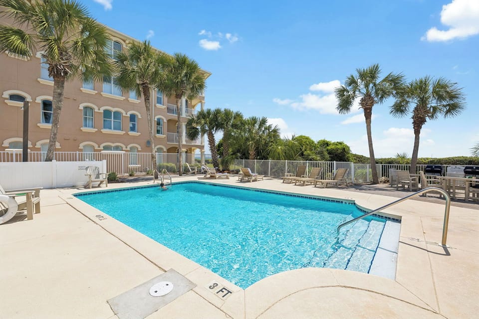 Dive into crystal-clear waters surrounded by swaying palms and comfortable loungers, where your perfect poolside retreat awaits under sunny skies.