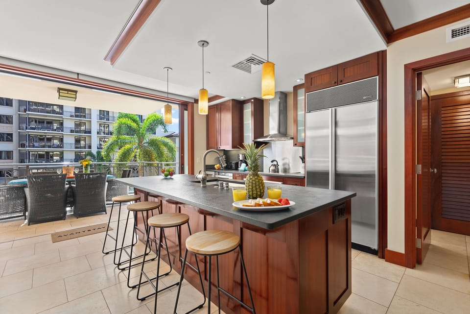 Kitchen with a large fridge and barstool seating at the island.