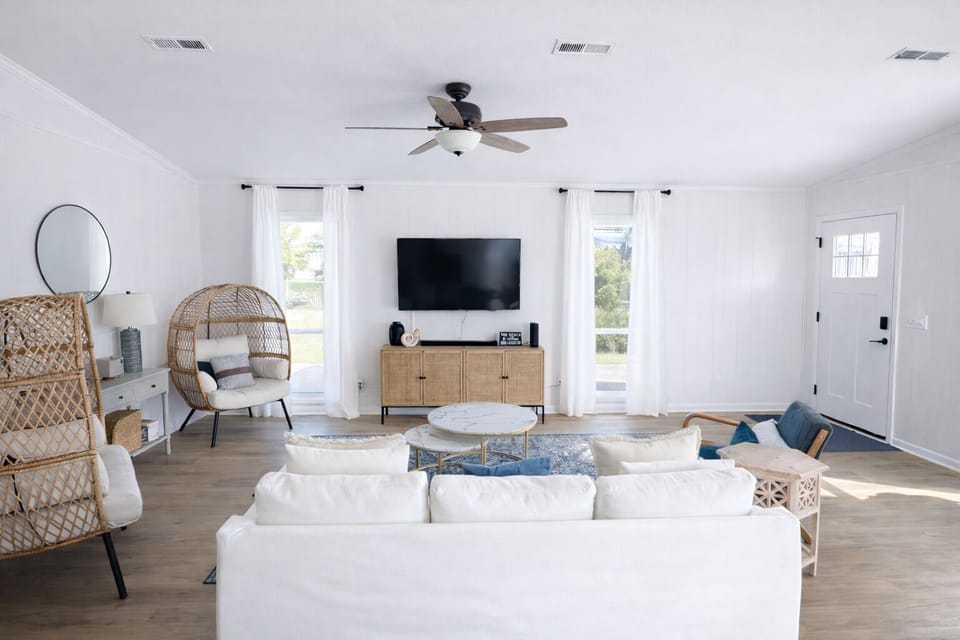 Large living room with SmartTV, comfortable couch, stylish wicker egg chairs