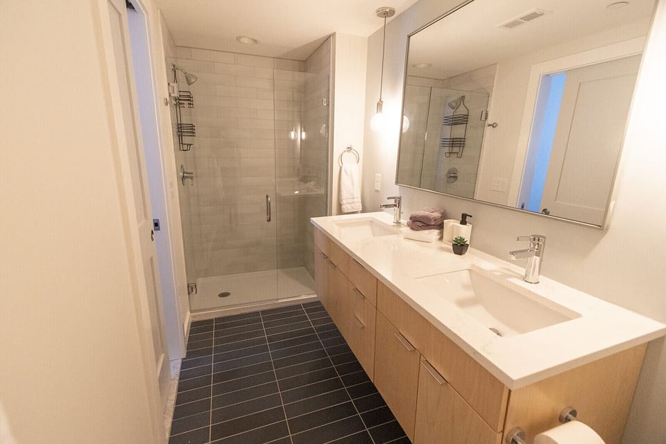 En suite master bath has a double sink with glass shower doors.