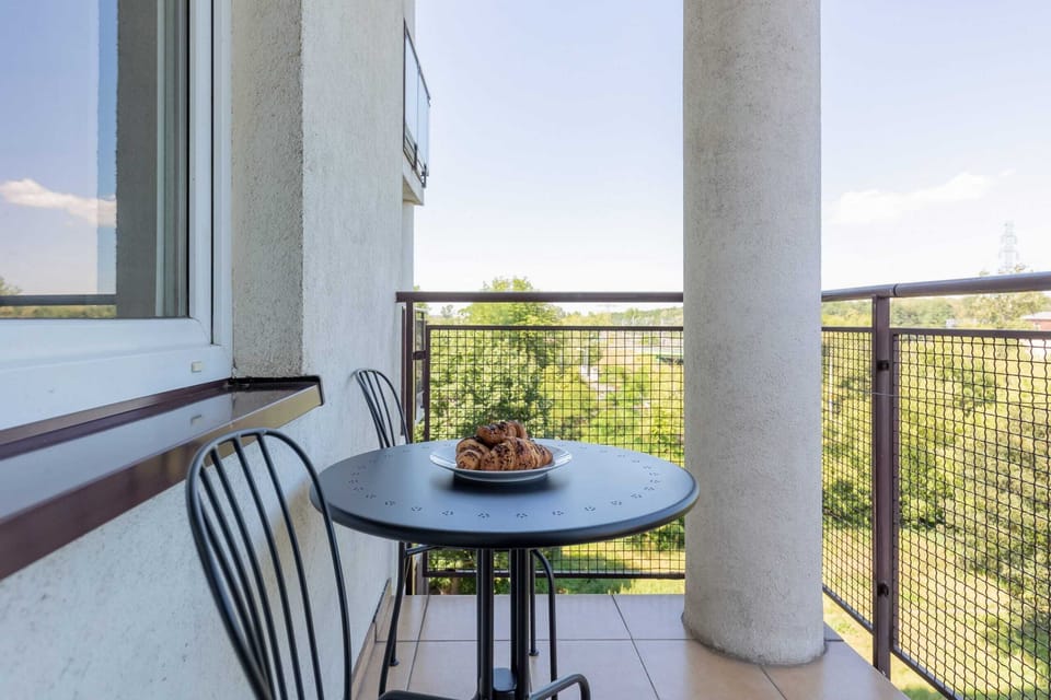 A cozy balcony with a table and chairs, offering a beautiful view.
