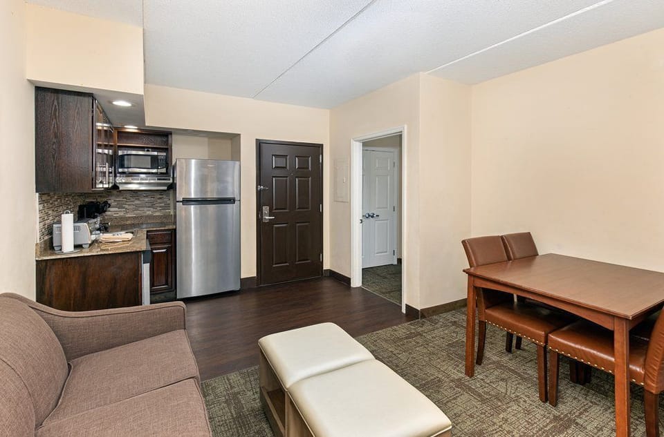 A modern living room highlights a cozy sofa and dining area, seamlessly connected to a functional kitchen space for your convenience.