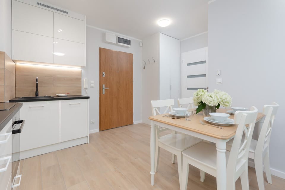 A dining area with a table set for two, connected to an open-plan living and kitchen area.
