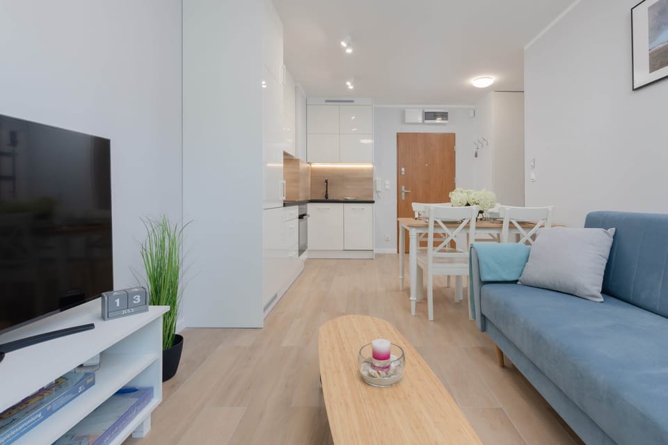 A modern open-plan living area, combining a sleek kitchen, dining table, and comfortable seating.
