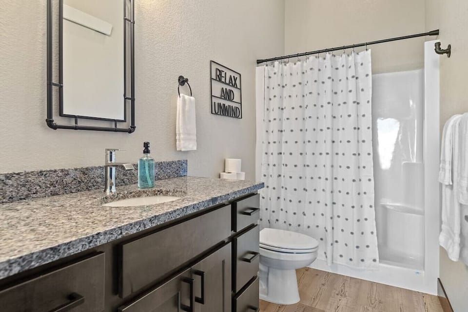 Enjoy a modern bathroom complete with a large vanity mirror, premium plush towels, and a refreshing shower for your comfort and convenience.