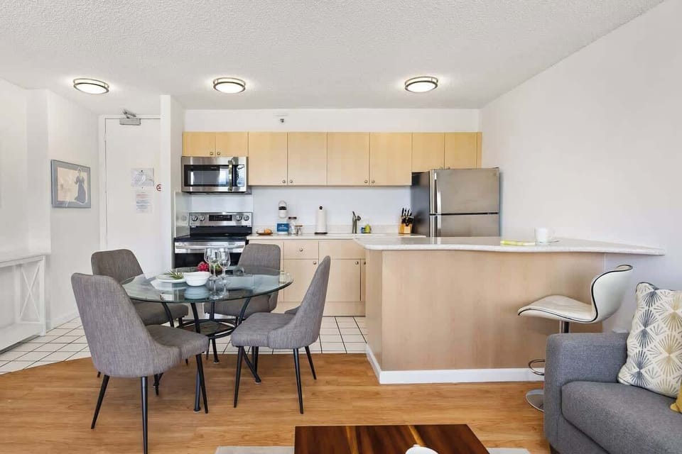 Cook with ease in the fully-equipped kitchen, featuring stainless steel appliances, a dining table with 4 chairs, and a breakfast bar for casual dining.