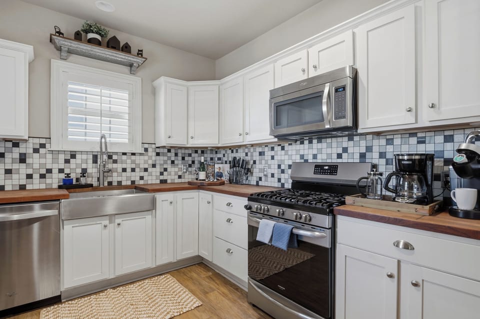 The kitchen is fully equipped for all your needs, featuring a microwave, stove, oven, dishwasher, and a large fridge.