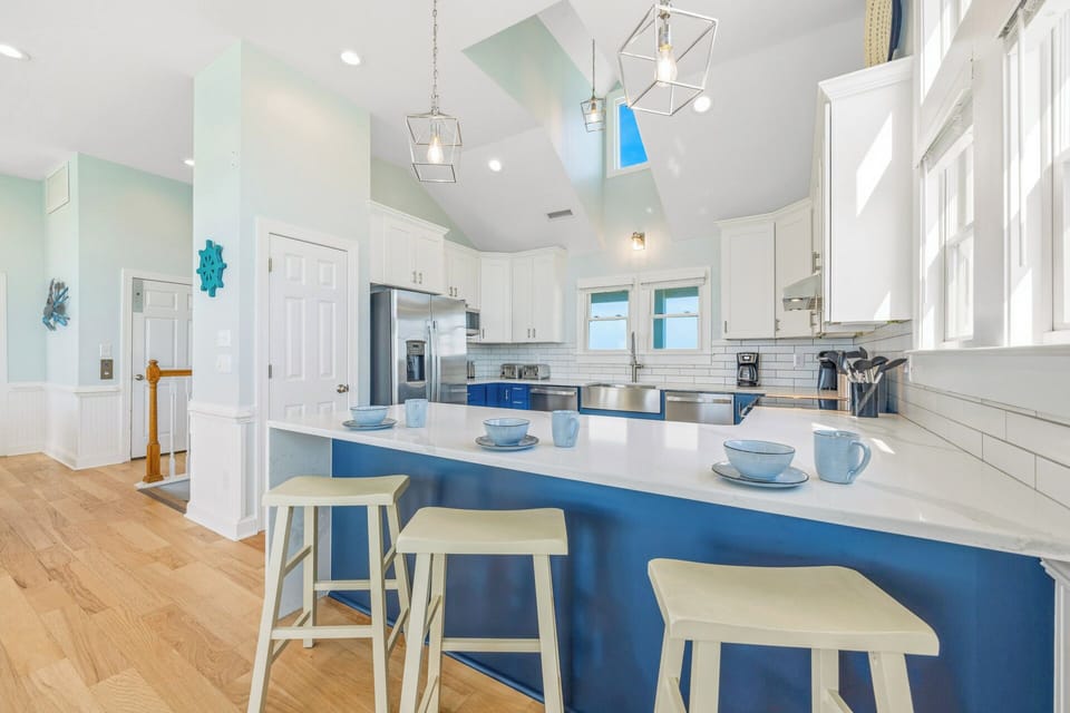Gather in this bright, airy kitchen where coastal hues meet modern comfort. The spacious island invites you to linger over morning coffee or enjoy casual meals together in style.