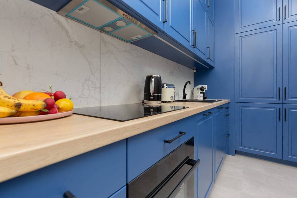 A functional and well-equipped kitchen with modern appliances and blue cabinetry.
