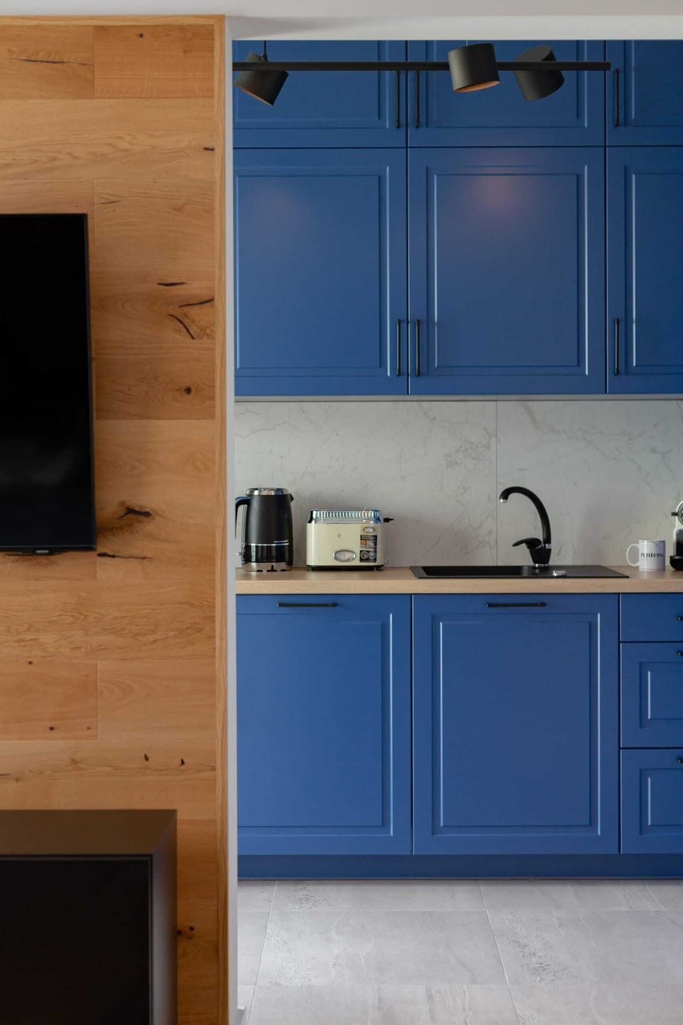 A compact and functional kitchenette with blue cabinets and a minimalist design.
